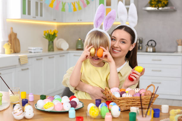 istock Mother and her cute son covering eyes with Easter eggs at table in kitchen 1780967560