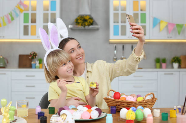 istock Mother making selfie with her cute son at table in kitchen. Painting Easter eggs 1780967580