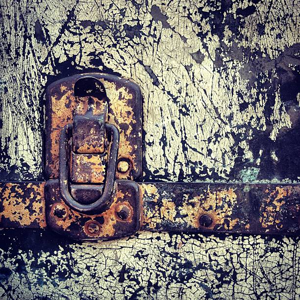A close up detail of a paint chipped metal trunk with rusted clasp