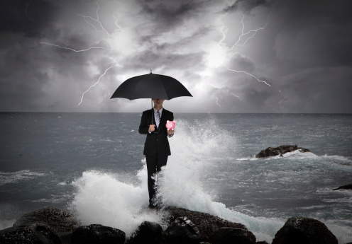 Business man under an umbrella standing on a rock in the sea with lightning sky, business concept