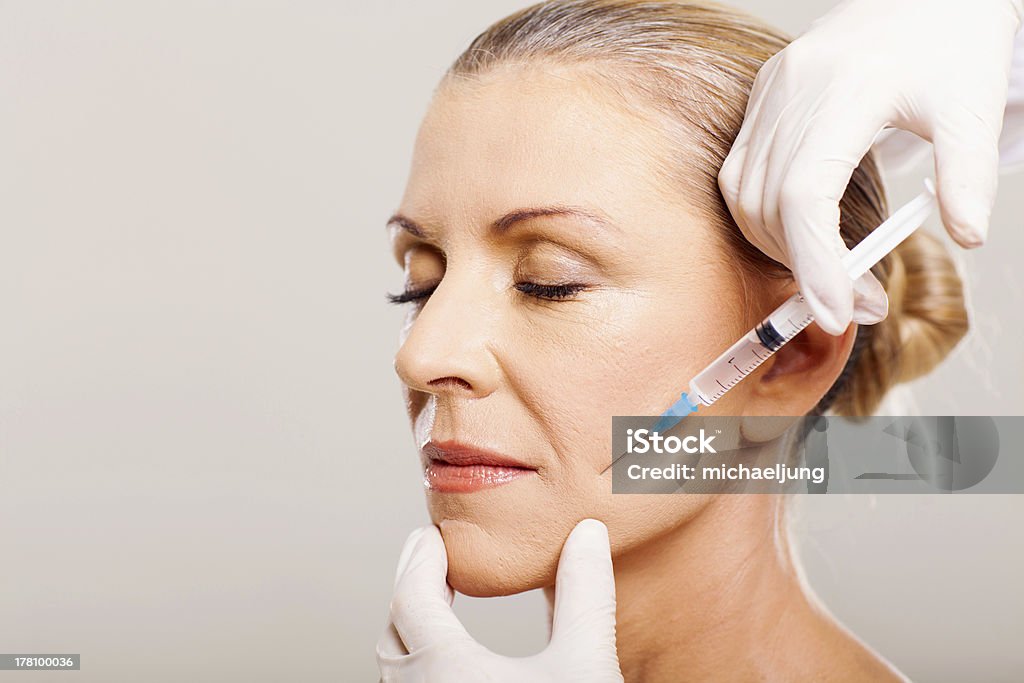 senior woman doing face lifting senior woman doing face lifting on her cheek Botulinum Toxin Injection Stock Photo