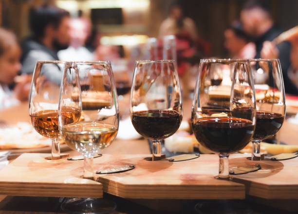 istock Dinner, wine tasting at old winery. Elegant wine pairing glasses filled with red, white, rose selections on rustic wooden table. Guests enjoy conversation in warm setting. Agrotourism, vineyard event 1781007619