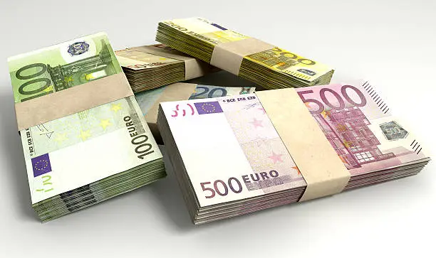 An assortment of euro note currency in scattered stacks on an isolated background