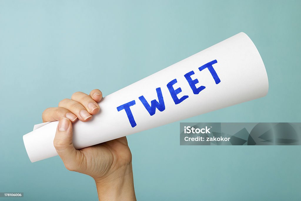 Mano mostrando azul un tweet palabra escrito a mano, conscientemente. Concepto de las redes sociales. - Foto de stock de Megáfono libre de derechos