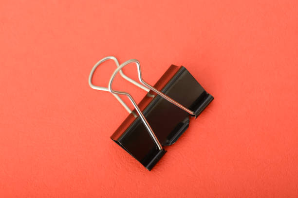 Paper clip isolated on a red background. A paper clip is a simple yet ingenious office tool designed to hold papers together