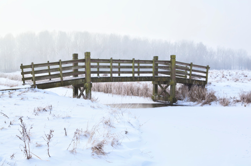 wooden bridge over frozen river in winter