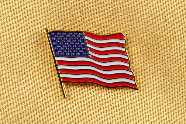 Stars and Stripes Flag Pin on gold satin background.