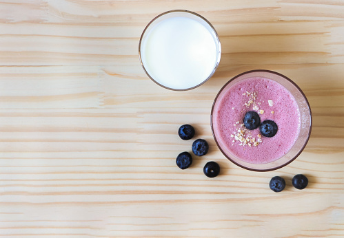 Top view of flat lay of  healthy drink, homemade Blueberry smoothies and a glass of milk with fresh blueberries on  wooden table background