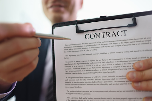 Businessman holds clipboard in hand pointing pen to contract papers. Man demonstrates rules written in agreement document before signing