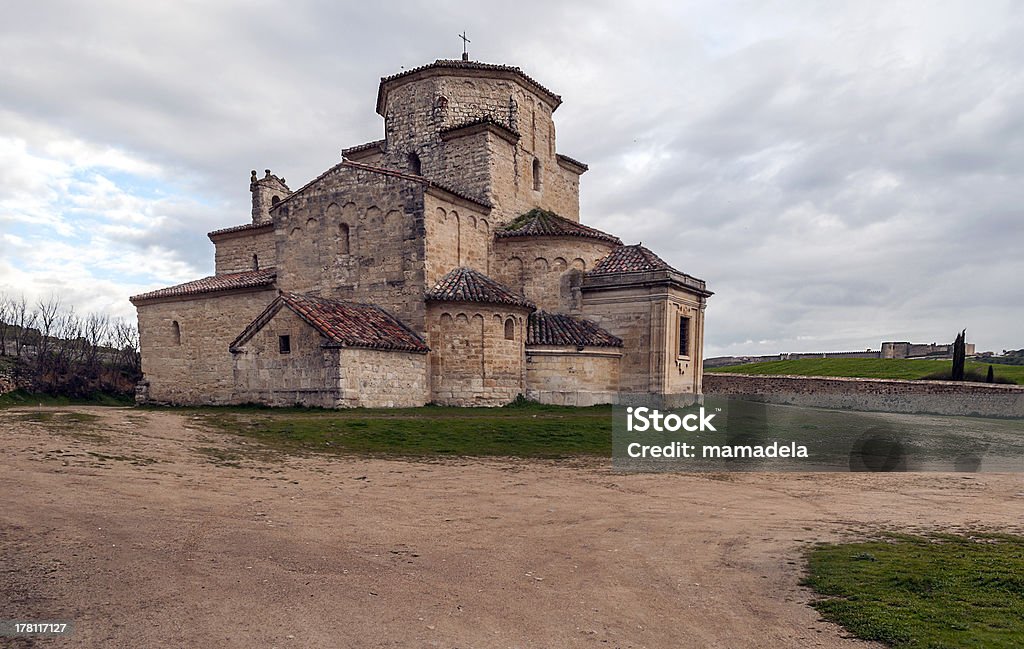 Church of Urueña Church of the Annunciation urueña located in Spain, is decorated with Lombard Romanesque style, is surrounded by fields. You can see a wall castle in the background Romanesque Stock Photo