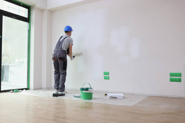 istock Foreman paints wall in white with roller dipped in bucket 1781190962