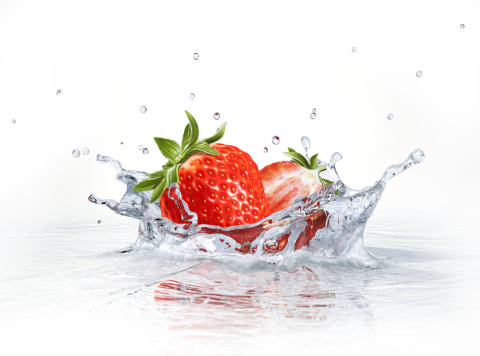 Strawberries falling into clear water, forming a crown splash. Viewed from a side, with white background.