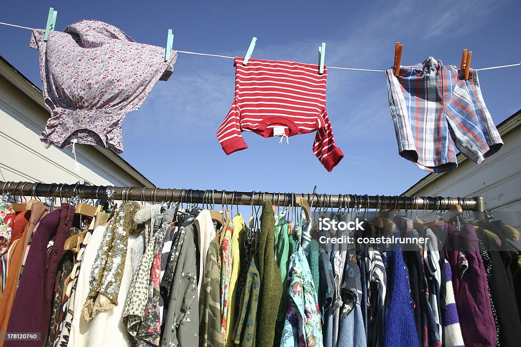 Colourful clothes pegged on a washing line outdoors Vintage clothing against a blue sky at a market in Southwold, Suffolk, on a glorious spring day, displayed on a railing and pegged on a line between two beach huts. Beach Hut Stock Photo