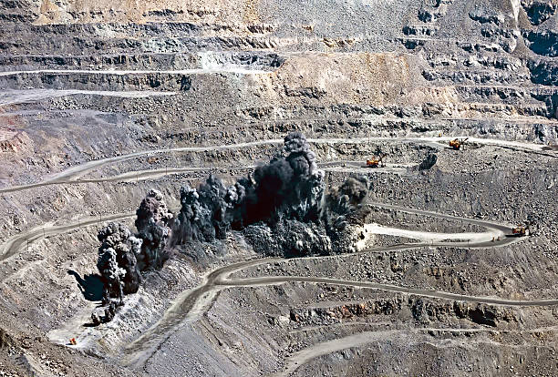 blast in open cast mine "excavators,trucks and heavy technics in open cast mine after blast among dust and smoke" explosive stock pictures, royalty-free photos & images