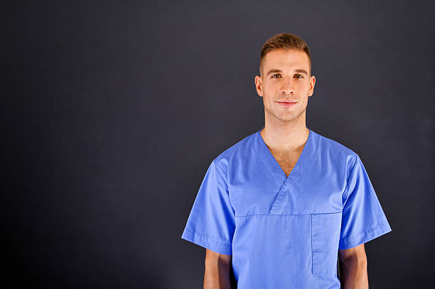 Doctor over dark background in blue shirt stock photo