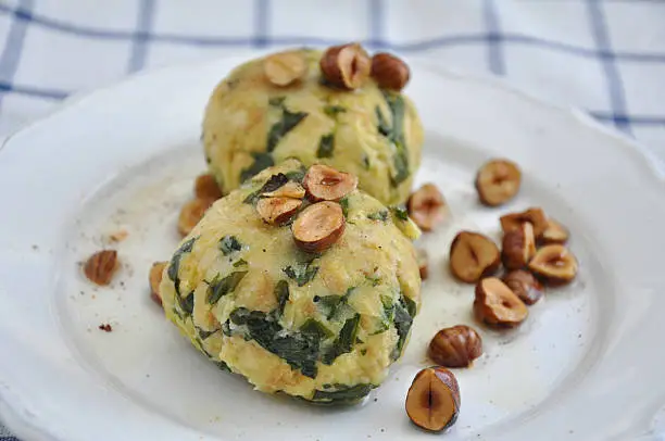 German boiled bread dumpling with spinach and hazelnut butter on a plate