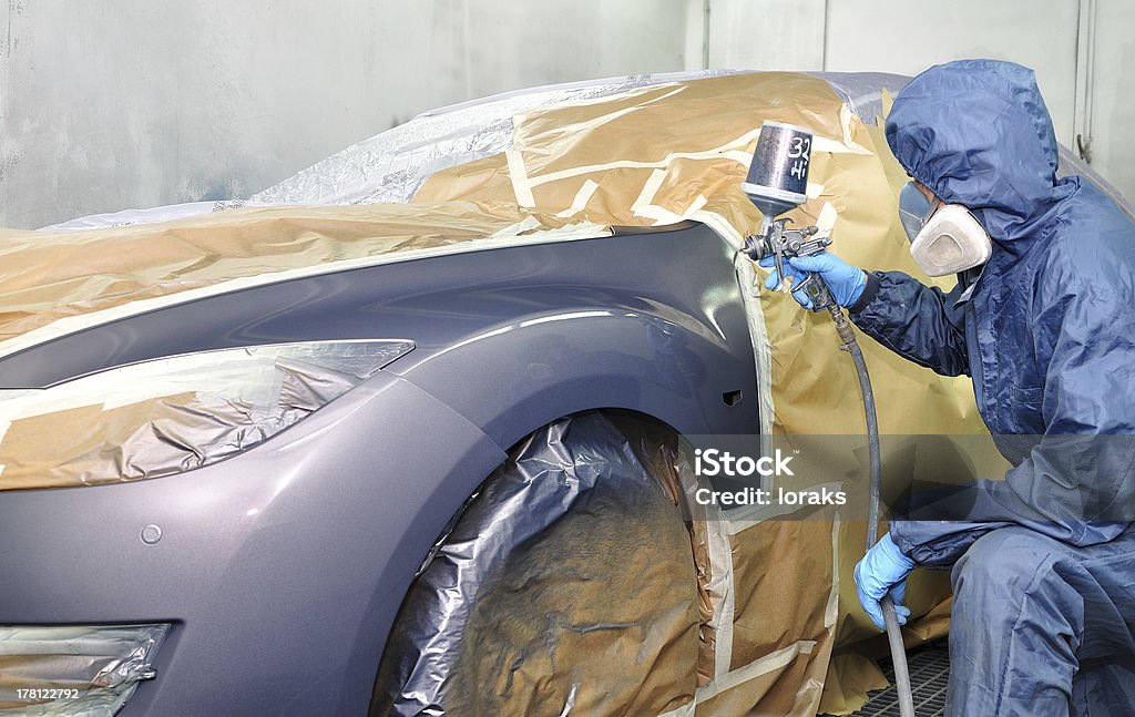 Professional car painting. Worker painting car in a paint booth. Man painting a silver car. Car Stock Photo