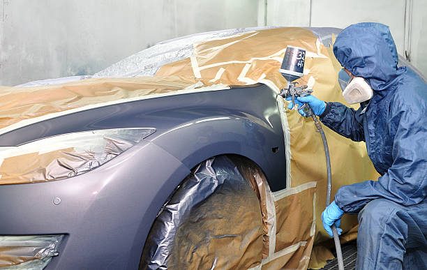 Professional car painting. Worker painting car in a paint booth. Man painting a silver car. bodywork stock pictures, royalty-free photos & images