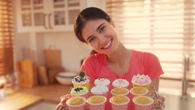 Woman showed fresh cupcakes with smiles in the kitchen,Slow motion