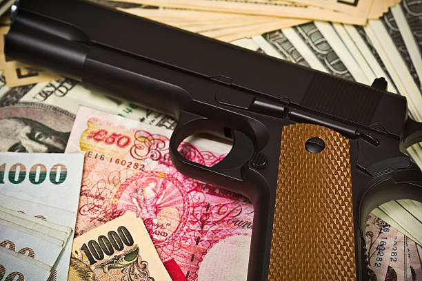 International Crime A gun placed on iternational currencies portrays linkage of international crime wrongdoer stock pictures, royalty-free photos & images