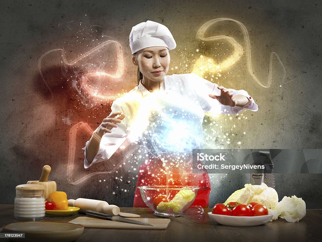 Asian female cooking with magic Asian female cooking with magic against color background Above Stock Photo