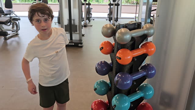 8-year-old boy places the dumbbell in the appropriate place in the gym
