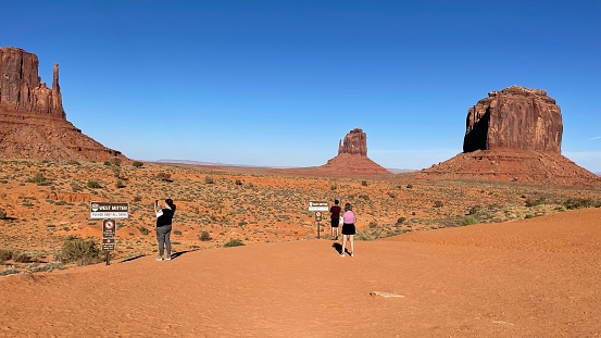 On September 29, 2023 in Monument Valley Utah these visitors are taking photographs of the amazing sandstone rocky outer cropping