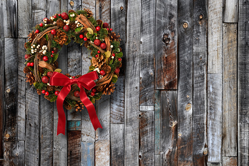 Christmas wreath hanging on a weathered old wood boards wall with copy space.