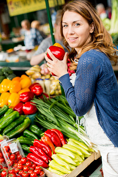 istock Young woman at vegetable stand holding a red pepper 178130961