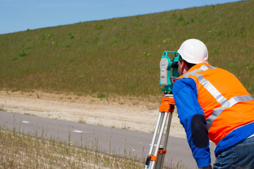 Engineer working with a modern theodolite or total station on a tripod