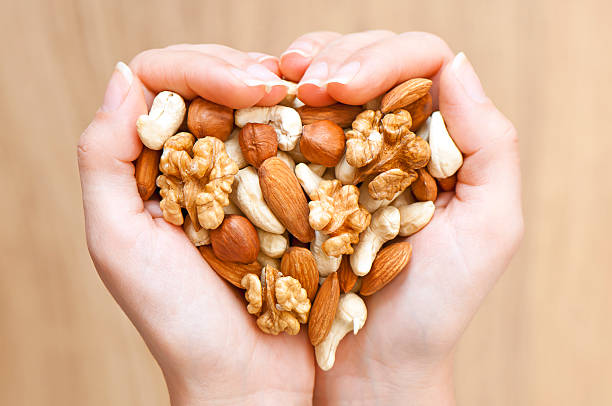 Nuts' mixture Various nuts in woman hands  forming heart shape nut variation healthy lifestyle pistachio stock pictures, royalty-free photos & images