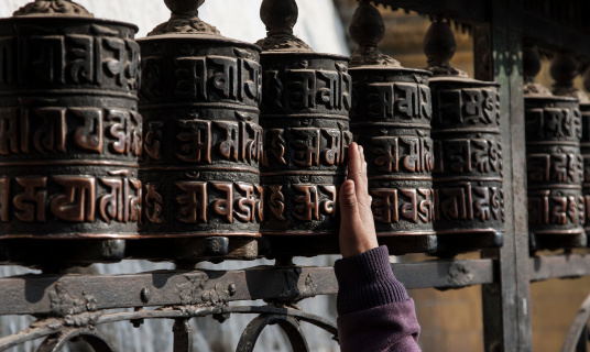 A young Buddhist kid trying to move prayer wheels at monastery in Kathmandu, Nepal.