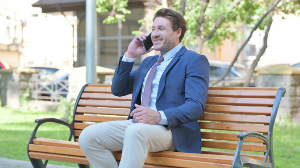 istock Middle Aged Businessman Talking on phone while Sitting Outdoor on a Bench 1781385991