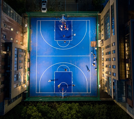 A group of off-duty workers playing basketball in the middle of the office building at night.