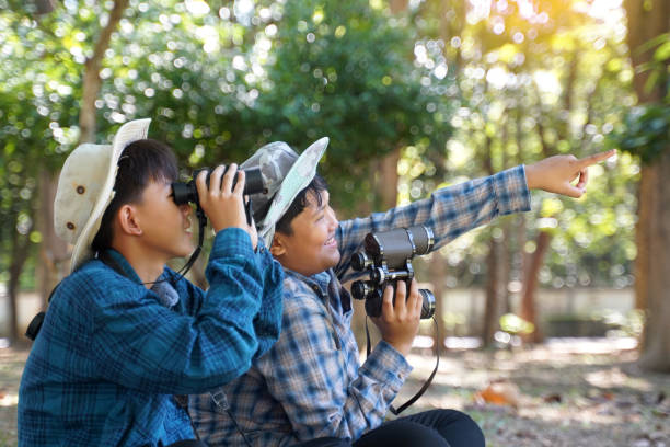 istock Asian boys use binoculars to look at birds in a community forest own. 1781403307