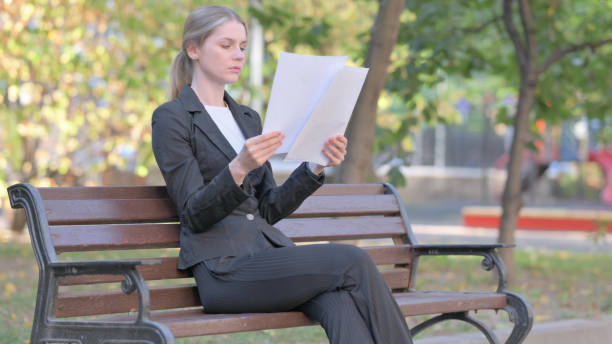 istock Businesswoman Reading Documents while Sitting Outdoor 1781410355