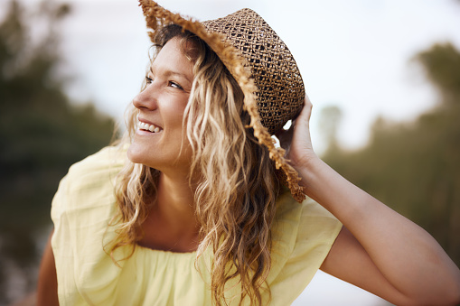 Young happy woman with a straw hat day dreaming in nature.