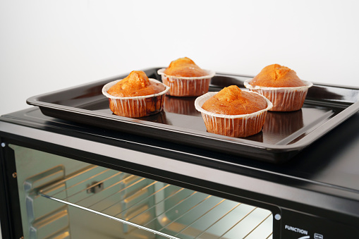 Electric mini oven and baked hot muffins close up photo