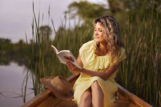 istock Young woman enjoying in book during spring day in a canoe. 1781427341