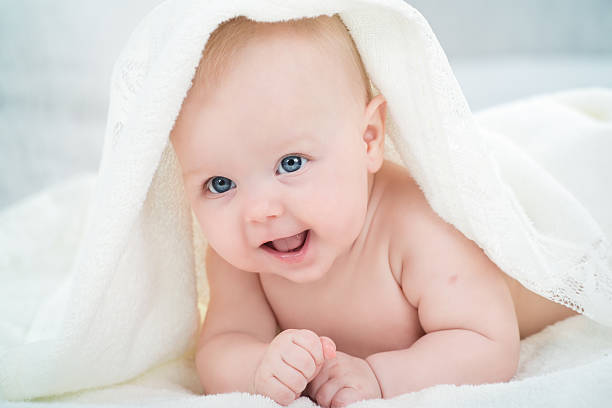 Bébé en regardant la caméra sous une couverture blanche - Photo