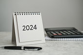 Desk calendar 2024, calculator and pen on the table