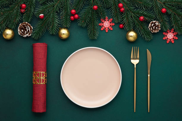 istock Clean empty plate, golden cutlery. Festive table setting with christmas decorations. Celebration xmas eve, flat lay. Red, gold and green accents. Fir cones on evergreen tree. Holiday banquet, top view 1781468861