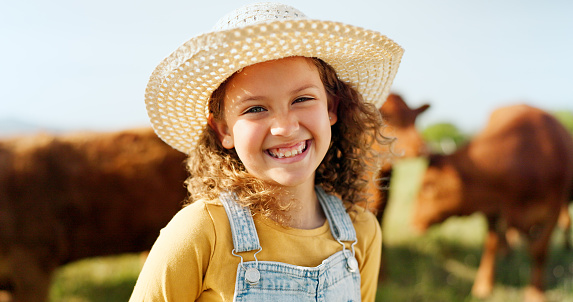 Happy little girl, portrait smile and farm with animals enjoying travel and nature in the countryside. Child smiling in happiness for agriculture, life and sustainability in farming and cattle