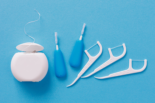 Top view of dental toothpicks and floss on blue background