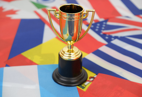 Golden trophy cup on national flags background. International championship and competition concept.