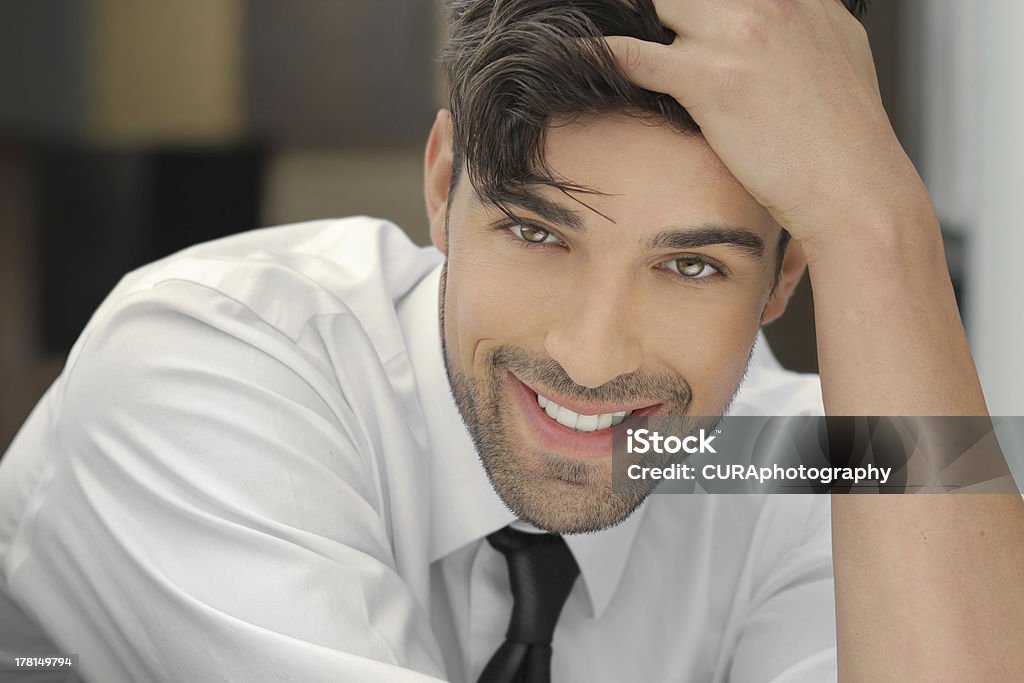 Smiling handsome guy Handsome young man leaning on his hand with nice big real smile Adult Stock Photo