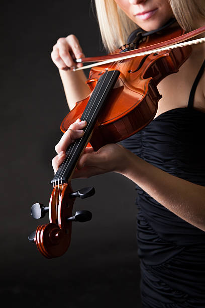 istock Beautiful young woman playing violin 178151047