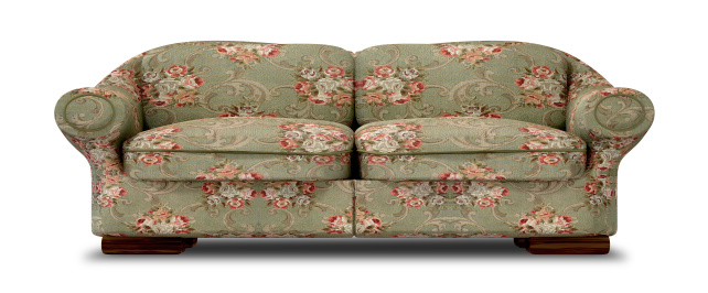 An old vintage sofa with a green and red floral fabric on an isolated background