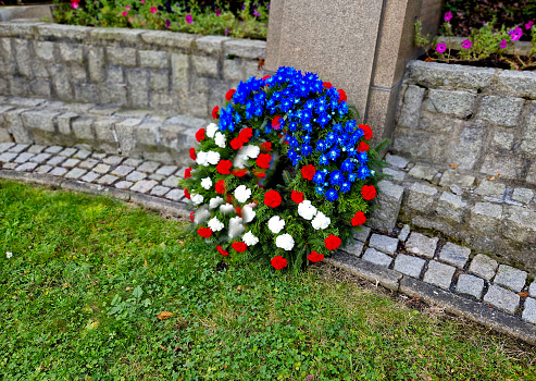 memorial to fallen soldiers in world wars. on a marble pedestal several floral arrangements in the shape of a circle wreaths with a ribbon in patriotic colors of France, the Czech Republic or Serbia, 28th october