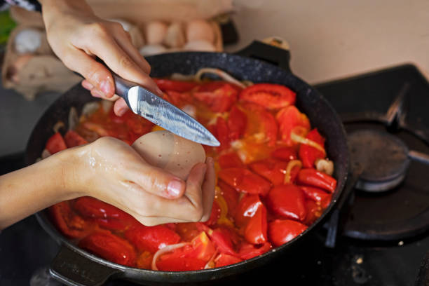 istock crack an egg into a frying pan with tomatoes 1781531415